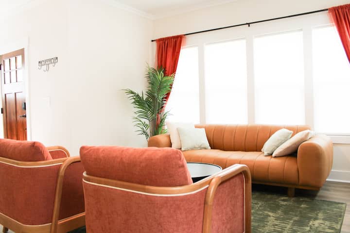 Bright living room with a tan sofa and rust-colored armchairs